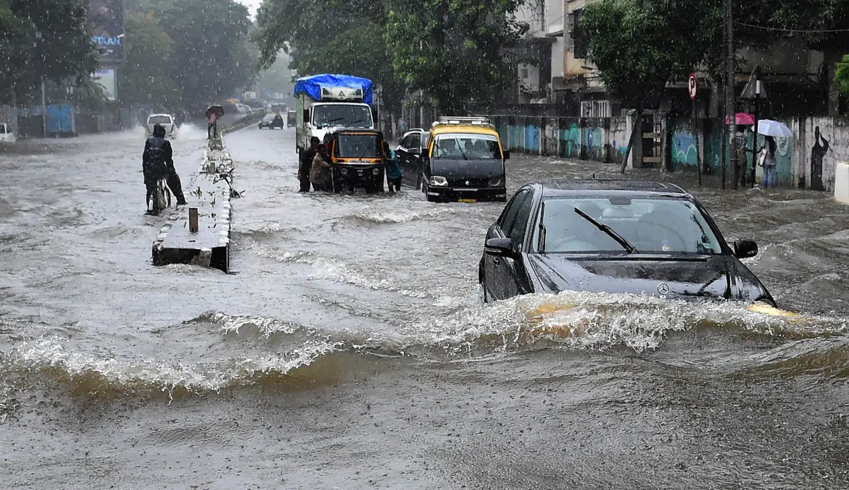 Sejumlah kendaraan melintasi banjir setelah hujan lebat di Mumbai, India (9/7). Mumbai dan daerah pinggiran lainnya telah mengalami hujan lebat semalaman yang mengakibatkan banjir. (AFP Photo/Indranil Mukherjee)