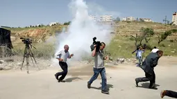 Wartawan Palestina berlari berhamburan setelah gas air mata ditembakkan pasukan Israel, Penjara Ofer Israel di Ramallah, Israel (26/4). Sejumlah wartawan menjadi sasaran tembakan gas air mata pasukan Israel. (REUTERS / Mohamad Torokman)