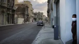 Seorang pria yang mengenakan masker berdiri di samping jalanan kosong saat penerapan jam malam di Havana, Kuba, Selasa (1/9/2020). Otoritas Kuba menerapkan lockdown selama 15 hari di Havana untuk keluar dari penularan COVID-19 tingkat rendah tetapi terus-menerus. (AP Photo/Ramon Espinosa)
