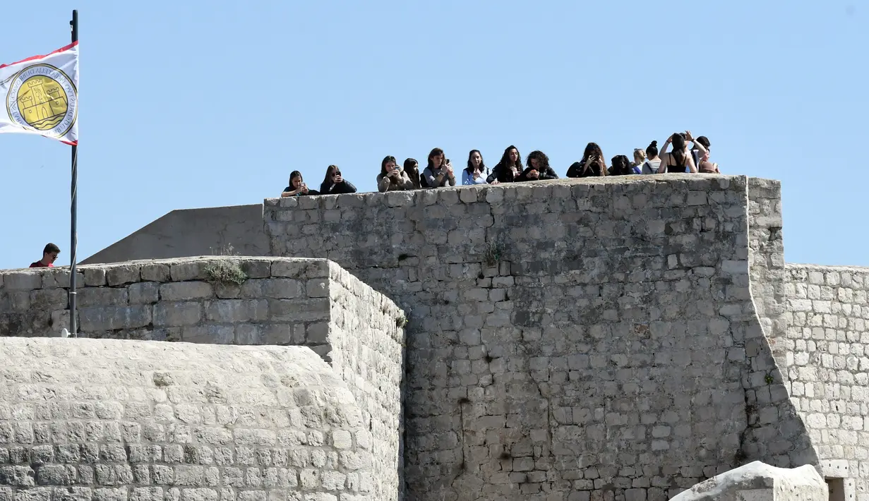 Wisatawan mengambil gambar dari atas benteng saat mengunjungi kota tua Dubrovnik di Kroasia pada 28 Maret 2019. Dubrovnik  yang telah dianugerahi UNESCO sebagai warisan dunia menjadi salah satu hal yang menjadi daya tarik wisatawan ke kota yang dikelilingi pulau ini. (Denis LOVROVIC / AFP)