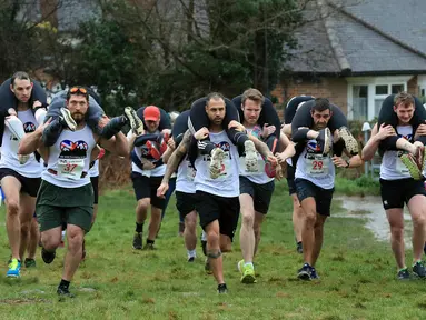 Para peserta bersaing dalam Lomba Lari Gendong Istri di The Nower, Dorking, Inggris, Minggu (3/3). Para suami harus menggendong istri mereka dari garis start hingga finish. (Gareth Fuller/PA via AP)