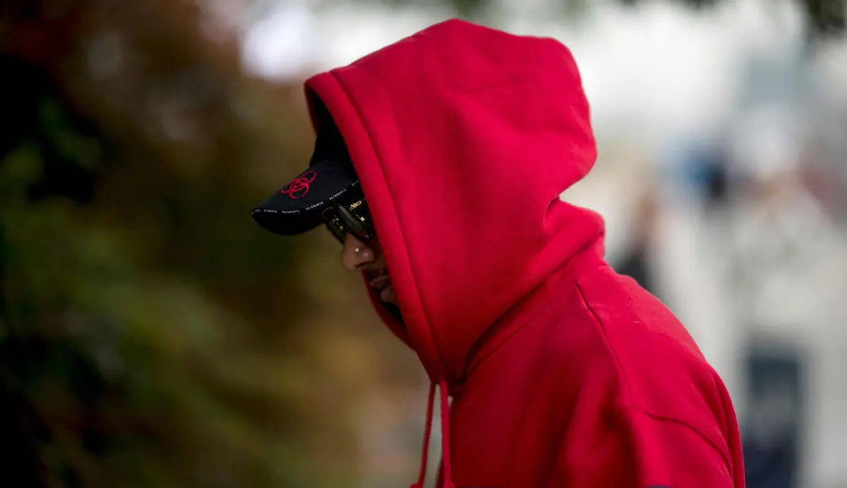 Pembalap Mercedes asal Inggris Lewis Hamilton berjalan di paddock sebelum Grand Prix Formula Satu China di Shanghai (12/4). Hamilton keren mengenakan kaca mata dan jaket berwarna merah. (AFP Photo/Johannes Eisele)