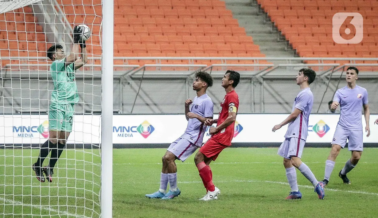 Kiper Indonesia All Star U-20 Ahludz Dzikri Fikri (kiri) menangkap bola saat bermain melawan FC Barcelona U-18 pada pertandingan International Youth Championship 2021 di Jakarta International Stadium, Jakarta, Rabu (13/4/2022). Pertandingan berakhir imbang 0-0. (Liputan6.com/Faizal Fanani)