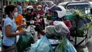 Seorang wanita membeli sayuran di sepanjang jalan karena pasar tetap tutup di tengah pembatasan lockdown yang diberlakukan untuk mencoba menghentikan lonjakan kasus virus corona COVID-19 di Phnom Penh, Kamboja, Selasa (11/5/2021). (TANG CHHIN Sothy/AFP)