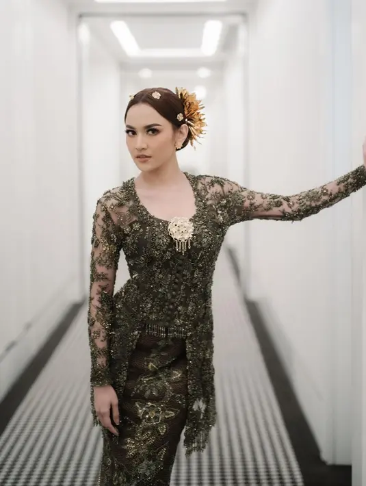 Mahalini tampak anggun saat mengenakan kebaya rancangan Asky Febrianti di hari lamarannya dengan Rizky Febian.  Kebaya warna hijau olive itu tampak mewah dengan detail bordir, lace, serta taburan payet. Aksen fringe pada bagian hem bawah menambah kesan glamor. [@evansirawan]