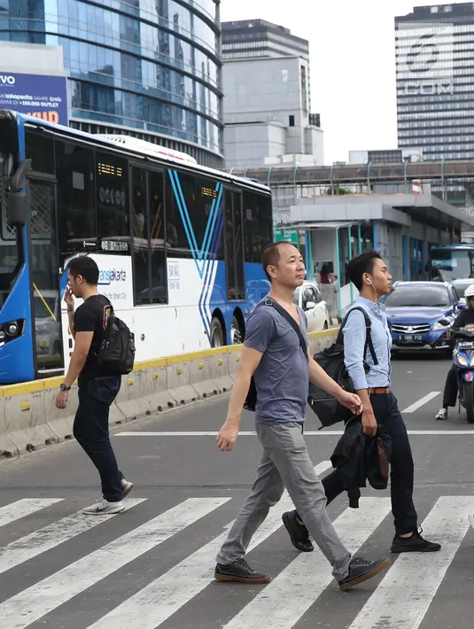 Warga menyebrang jalan Sudirman di kawasan Tosari, Jakarta, Jumat (14/12). Penggunaan pelican crossing di kawasan ini menggantikan fungsi Jembatan Penyebrangan Orang (JPO) Tosari yang akan dibongkar. (Liputan6.com/Helmi Fithriansyah)