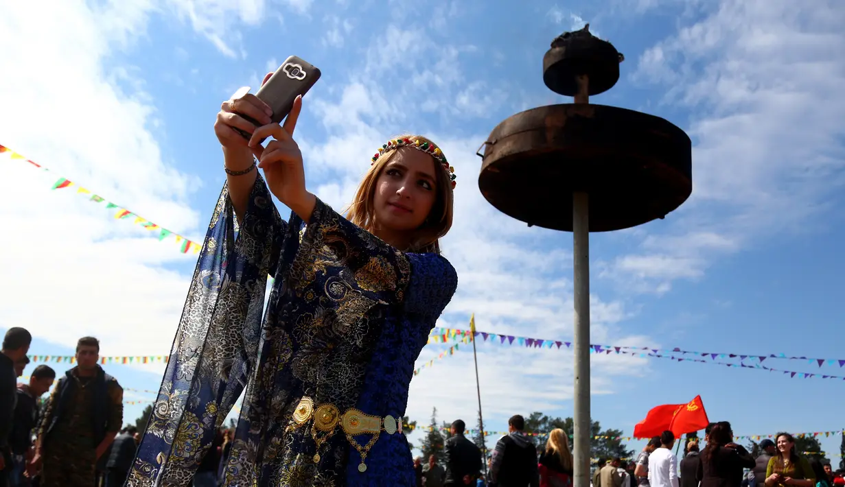 Seorang wanita Kurdi Suriah berselfie selama Perayaan Newroz di Kota Qamishli, Suriah (21/3). Newroz, juga dikenal sebagai Nawroz atau Nowruz adalah sebuah Festival Tahun Baru Persia Kuno. (AFP Photo / Delil Souleiman)