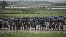 Pengungsi Muslim Rohingya menunggu antrean distribusi makanan saat hujan di kamp pengungsi Nayapara, Bangladesh (6/10). Bangladesh akan membangun kamp pengungsi terbesar di dunia untuk menampung 800.000 orang. (AFP PHOTO/Fred Dufour)