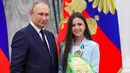 <p>Presiden Rusia Vladimir Putin berpose dengan figure skater Kamila Valieva selama upacara penghargaan untuk pemenang medali Olimpiade Musim Dingin Beijing 2022 di Kremlin di Moskow (26/4/2022). (Mikhail KLIMENTYEV/SPUTNIK/AFP)</p>