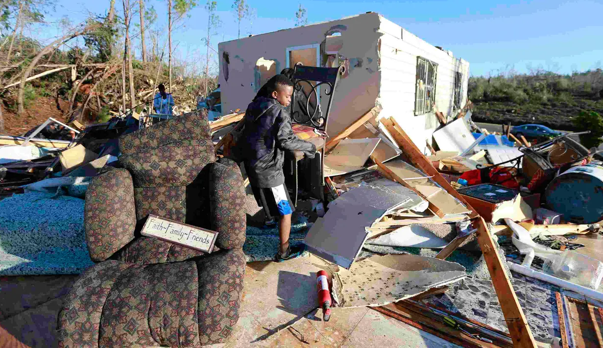 Jaquish Fox (10) membantu bibinya menyelamatkan barang yang masih bisa dipakai setelah tornado menghantam Holly Springs, Mississipi, Kamis (24/12). Badai tornado menerjang wilayah Amerika Serikat bagian selatan dan menewaskan 11 orang.  (REUTERS)