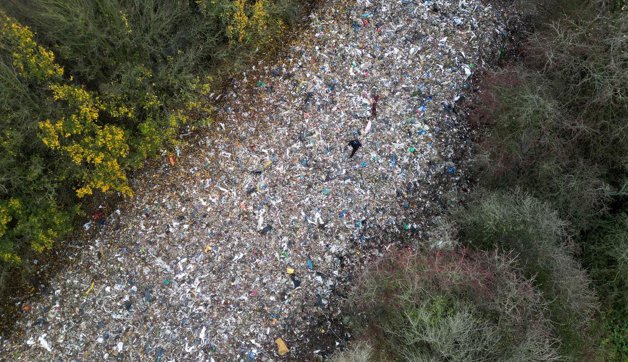 Badan Lingkungan Hidup (Environment Agency) setempat sedang menyelidiki insiden tersebut dan telah mendesak saksi untuk melapor. Tampak foto udara memperlihatkan aktivis lingkungan sedang merekam konten untuk media sosial di tumpukan sampah ilegal yang besar, yang dibuang di sebuah ladang antara Sungai Cherwell dan Jalan A34 dekat Kidlington, Oxfordshire, di barat London pada 16 November 2025. (Justin TALLIS/AFP)