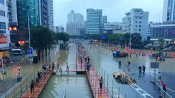 Sejumlah warga berada di tengah banjir saat menenggelamkan jalanan protokol Kota Fuzhou, China, Rabu (28/9). Bencana alam ini memaksa Tiongkok menutup sekolah-sekolah dan membatalkan puluhan jadwal penerbangan. (China Daily/via REUTERS)
