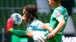 Pemain Werder Bremen,  Ludwig Augustinsson, berebut bola dengan pemain Wolfsburg, Kevin Mbabu, pada laga Bundesliga di Weserstadion Minggu (7/6/2020). Werder Bremen takluk 0-1 dari Wolfsburg. (AFP/Patrik Stollarz)