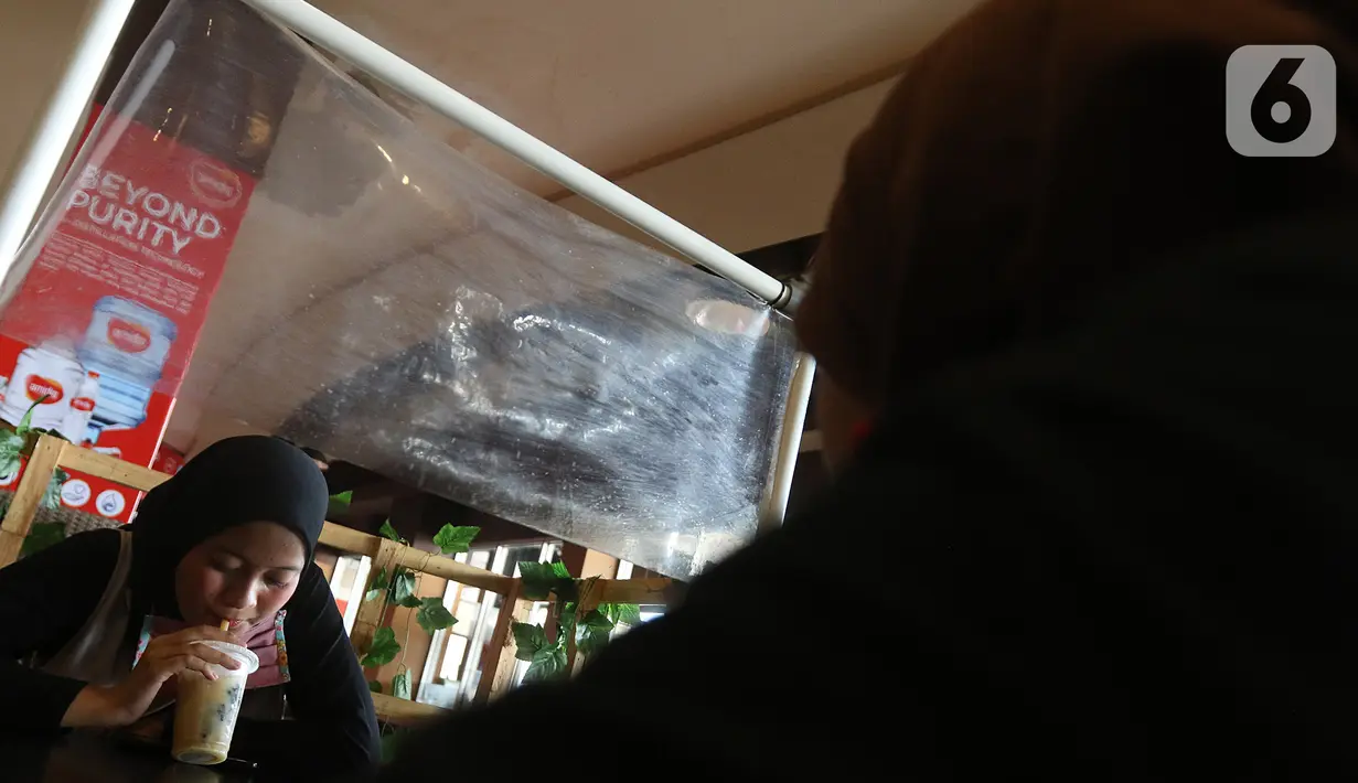 Pengunjung minum di sela-sela pembatas plastik di salah satu restoran Mall Bekasi, Jawa Barat, Minggu (7/6/2020). Sejumlah tempat makan mulai menerapkan protokol kesehatan untuk pengunjung yang makan ditempat untuk mencegah penyebaran wabah COVID-19. (Liputan6.com/Herman Zakharia)