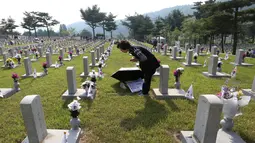 Warga Korea Selatan, Kim Soon berdoa di depan batu nisan ayahnya yang meninggal selama Perang Korea di pemakaman nasional, Seoul, Korea Selatan, Rabu (6/6). Kegiatan ini dilakukan dalam Memorial Day. (AP Photo/Ahn Young-joon)