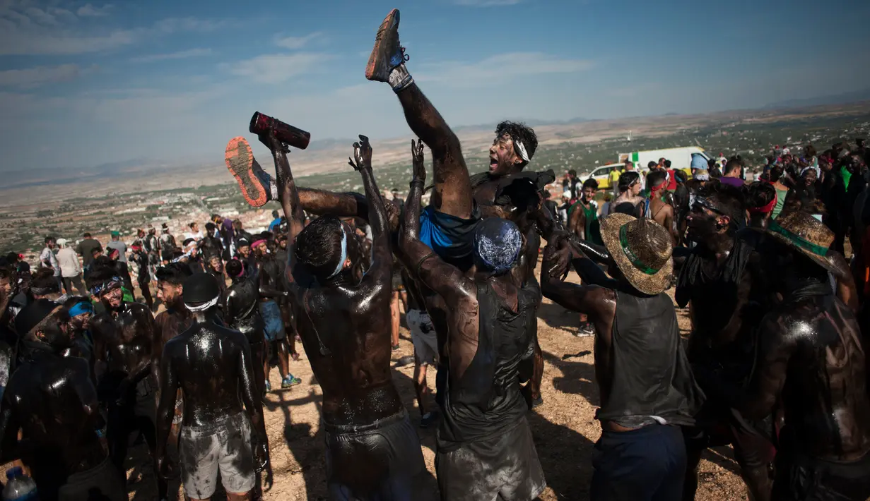 Peserta saling menyiram minyak hitam ke tubuh mereka dan melemparkannya ke udara selama festival tradisional Cascamorras di Baza, Spanyol, Rabu (6/9). Festival ini dianggap juga sebagai festival paling kotor yang ada di Spanyol. (JORGE GUERRERO/AFP)