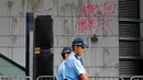 Polisi berjaga-jaga di depan tembok bertulis kata-kata China 'Penarikan dan Pembebasan' di pintu masuk utama kantor polisi di Hong Kong, Sabtu (22/6/2019). Markas polisi tersebut jadi korban aksi vandalime demonstran dalam lanjutan aksi unjuk rasa menolak RUU Ekstradisi. (AP Photo/Vincent Yu)