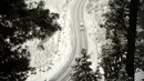 Kendaraan melintasi sepanjang jalan yang tertutup salju di Gulmarg, sekitar 55 km sebelah utara Srinagar, Kashmir, Selasa (3/1). Gelombang dingin yang melanda Kashmir kian parah hingga mencapai suhu di bawah nol derajat celcius. (Tauseef Mustafa/AFP)