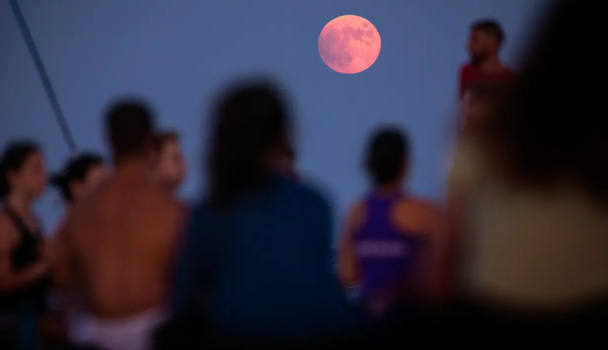 Fenomena gerhana bulan sebagian (parsial) terlihat ketika warga mengambil bagian dalam sesi yoga di depan laut Mediterania di Barcelona, Spanyol pada Selasa (16/7/2019). Gerhana bulan parsial ini bisa diamati dari Amerika Selatan, Eropa, Afrika, Asia dan Australia. (AP Photo/Emilio Morenatti)