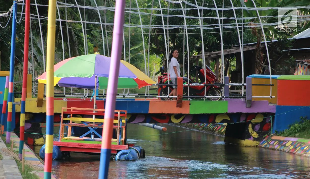 Warga melintasi perahu apung di Wisata Air Toino, Desa Talulobutu, Kecamatan Tapa, Kabupaten Bone Bolango, Gorontalo, Sabtu (30/3). Selain sebagai sosialisasi menjaga kebersihan lingkungan, wisata air ini juga sengaja dibuat agar bisa menarik perhatian. (Liputan6.com/Arfandi Ibrahim)