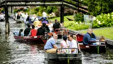 Wisatawan menaiki perahu menyusuri sungai di Giethoorn yang menjadi tujuan wisata favorit di Belanda pada 6 Agustus 2019. Mendapat julukan 'Venice of the North', kota tersebut menggunakan kanal-kanal sebagai jalan dan lalu lalang transportasi sehari-hari. (Robin van Lonkhuijsen/ANP/AFP)