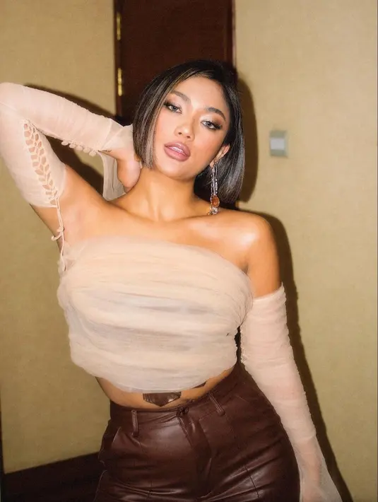 Ide crop top cantik lainnya dari Marion Jola. Di sini Marion terlihat mengenakan crop top berbahan chiffon dengan warna netral. Yang lebih menarik, crop topnya ini memiliki sambungan ke lengan panjangnya dengan detail tali. Foto: Instagram.
