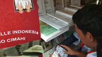 Seorang pengunjung "melihat" buku dan CD yang diterbitkan oleh BLBI Abiyoso (Liputan6.com/Giovani Dio Prasasti)