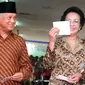 Presiden BJ Habibie didampingi istrinya Ainun Habibie menunjukkan surat suara sebelum melakukan pencoblosan dalam pemilu di Jakarta, 7 Juni 1999. Makam Habibie bakal bersebelahan dengan sang istri tercinta, Ainun Habibie. (AFP Photo/Agus Lolong)