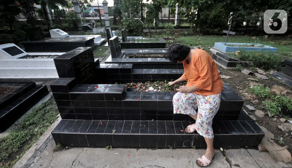 Keluarga membersihkan makam saat ziarah di kompleks pemakaman Gereja Tugu, Semper, Jakarta, Senin (23/12/2019). Ziarah menjadi tradisi keluarga keturunan Portugis di Kampung Tugu menjelang Hari Raya Natal. (merdeka.com/Iqbal Nugroho)