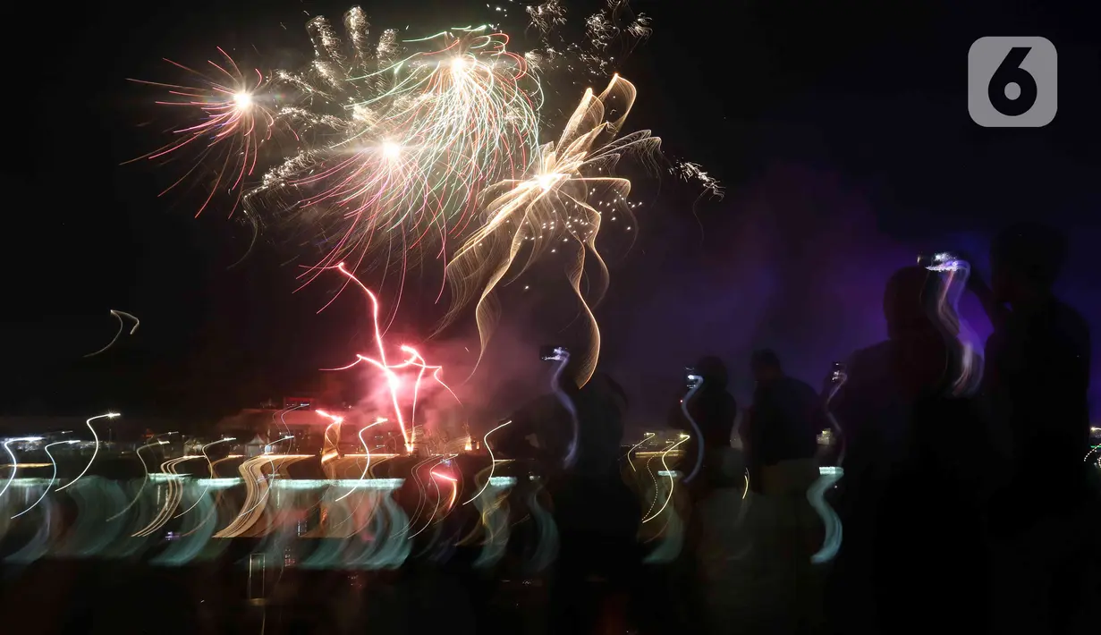 Warga menyaksikan pesta kembang api saat perayaan malam puncak Tahun Baru 2023 di Danau Archipelago, Taman Mini Indonesia Indah (TMII), Jakarta, Minggu (1/1/2023). Sebelumnya, Pemprov DKI Jakarta menunjuk TMII untuk menjadi pusat perayaan tahun baru 2023 di Jakarta. (Liputan6.com/Herman Zakharia)