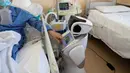 Pasien positif virus corona menggunakan layar sentuh robot di rumah sakit 'Ospedale di Circolo', di Varese, Italia pada 8 April 2020. Sebanyak enam unit robot yang tampak seperti manusia dan berjalan di atas roda ini membantu kinerja staf medis dalam merawat pasien Covid-19. (AP/Luca Bruno)