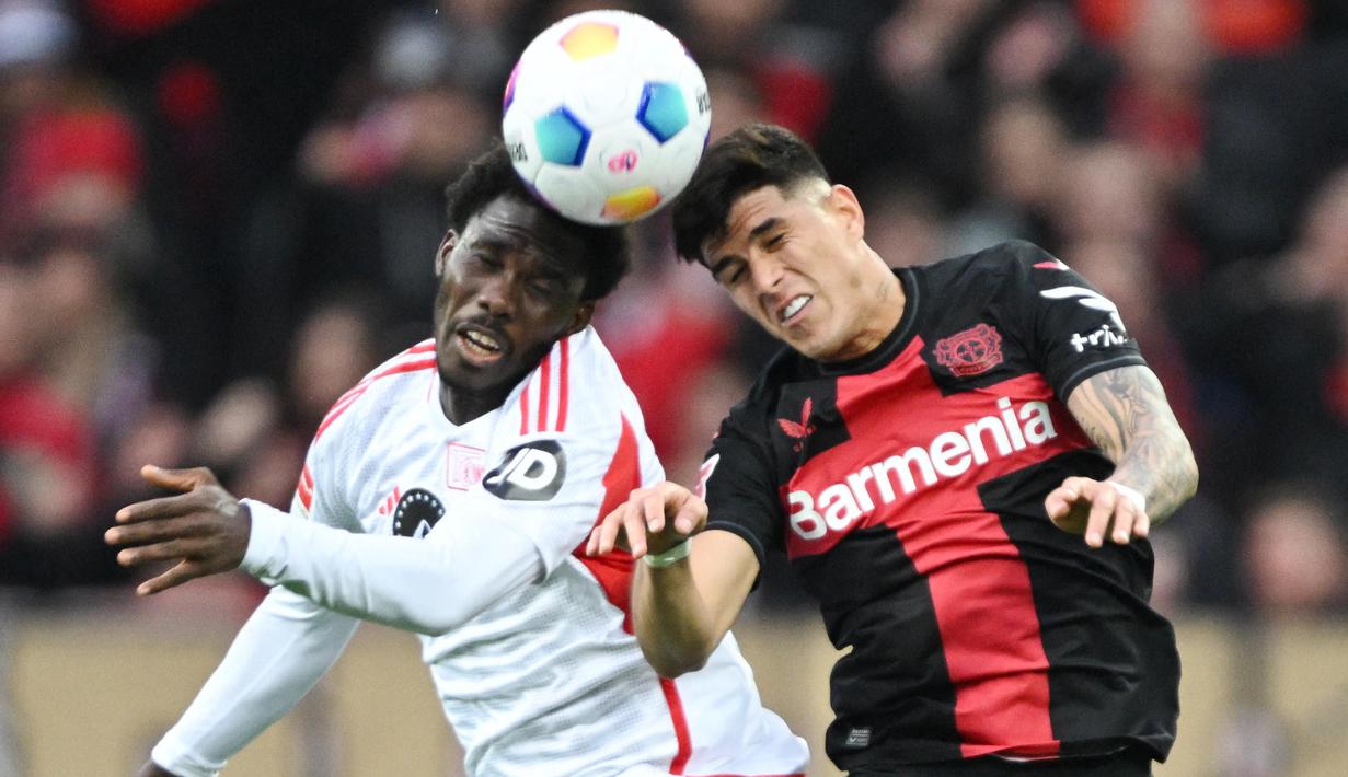 Pemain Bayer Leverkusen, Piero Hincapie, duel udara dengan pemain Union Berlin, David Datro Fofana, pada laga Bundesliga di Bay Arena, Minggu (12/11/2023). (AFP/Ina Fassbender)