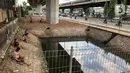 Sejumlah warga memancing ikan di kubangan yang berada di Jalan DI Panjaitan, Jatinegara, Jakarta, Selasa (16/6/2020). Meski telah dipagari, sejumlah warga tetap memancing ikan di lokasi yang merupakan saluran pembuangan tersebut. (Liputan6.com/Immanuel Antonius)