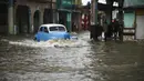 Sebuah mobil tua Amerika Serikat melewati jalan yang banjir di Havana, Kuba, 30 Juni 2021. Hujan deras dan selokan yang tidak berfungsi menyebabkan banjir di jalan-jalan di Havana. (YAMIL LAGE/AFP)