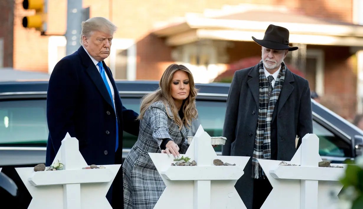 Melania Trump (tengah) didampingi Presiden Donald Trump (kiri) dan Rabbi Jeffrey Myers (kanan) saat meletakkan bunga di monumen peringatan penembakan maut di sinagog Tree of Life, Kota Pittsburgh, Pennsylvania, AS, Selasa (30/10). (AP Photo/Andrew Harnik)