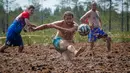 Pemain sepak bola rawa berebut bola dalam turnamen sepak bola rawa di desa Pogy, 60 km (37 mil) dari St. Petersburg, Rusia pada 22 Juni 2019. Meski lumpur menghambat kecepatan atlet, olahraga yang berasal dari Finlandia ini digemari di beberapa negara. (AP/Dmitri Lovetsky)