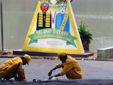 Petugas melakukan perbaikan jalan masuk Setu Babakan, Jakarta, Jumat (14/7). Setu Babakan akan menjadi lokasi pelaksanaan Lebaran Betawi 2017 yang akan digelar pada 21 - 23 Juli 2017. (Liputan6.com/Helmi Fithriansyah)