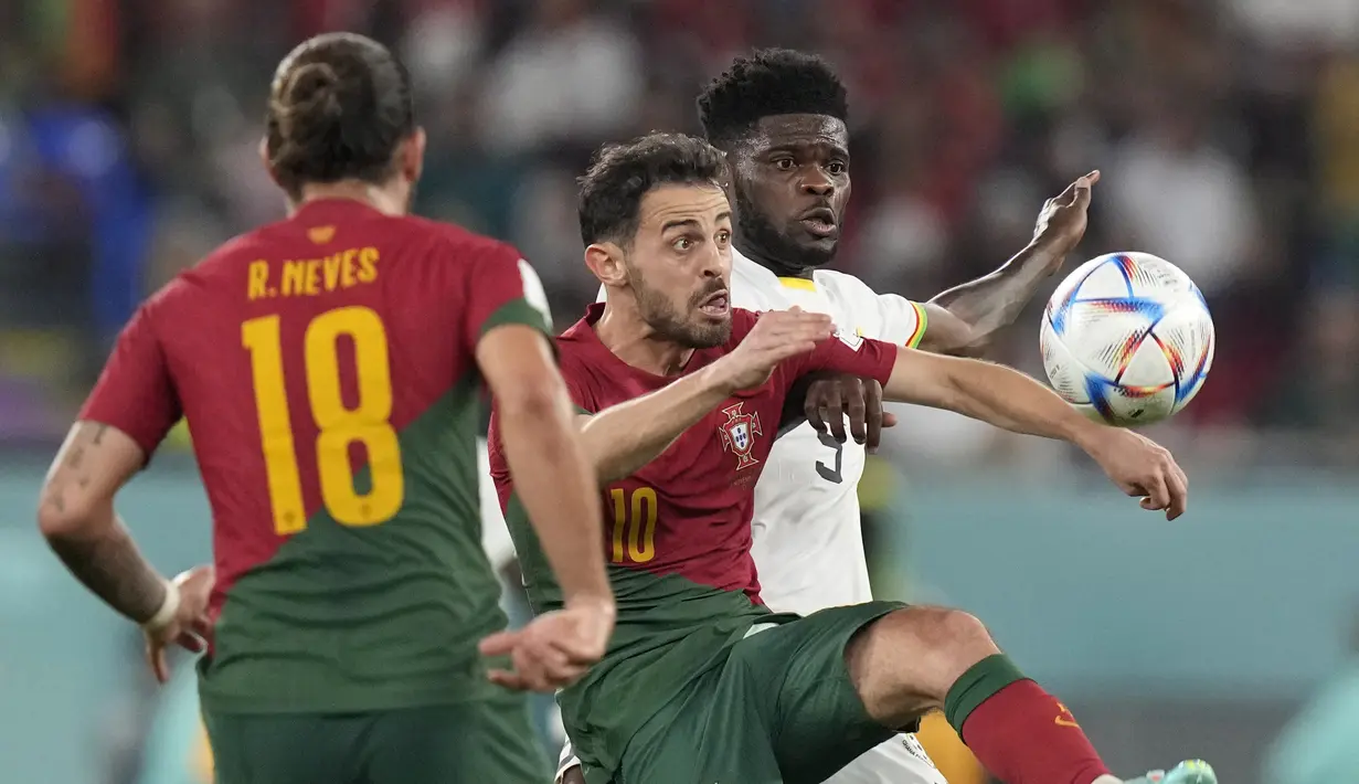 Gelandang Portugal Ruben Neves (kiri) menyaksikan gelandang Ghana Thomas Parteybersaing dengan rekannya, Bernardo Silva pada duel grup H Piala Dunia 2022 di stadion 974, Kamis (24/11/2022). Menang 3-2, tiga gol Portugal dicetak Cristiano Ronaldo, Joao Felix dan Rafael Leao. (AP Photo/Darko Bandic)