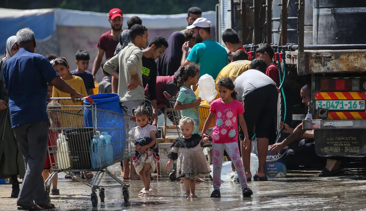 Di kamp Nuseirat, Jalur Gaza Tengah,para pengungsi langsung mengisi wadah mereka ketika bantuan air bersih yang dibawa salah satu truk bantuan tiba. (Eyad BABA/AFP)