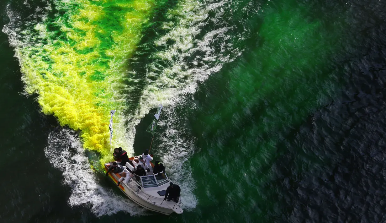 Petugas menggunakan kapal untuk menyemprotkan pewarna  hijau khusus ke sungai Chicago, AS selama perayaan St. Patrick's Day, 11 Maret 2017. Sungai itu setiap tahun mengalami perubahan warna demi memikat wisatawan. (John J. Kim/Chicago Tribune melalui AP)