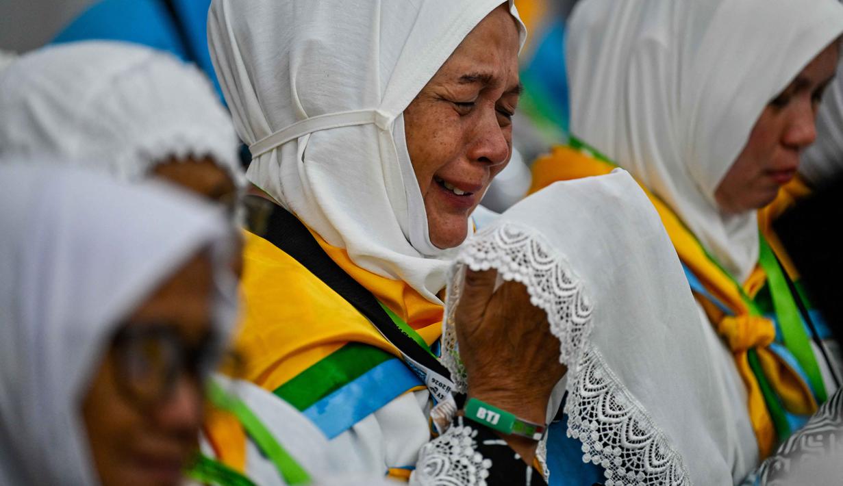 Seorang calon jemaah haji Indonesia menangis sambil berdoa selama sesi pelatihan keselamatan pra-keberangkatan di pusat embarkasi haji Banda Aceh pada Kamis 14 Mei 2026. (CHAIDEER MAHYUDDIN/AFP)