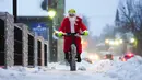 Brian Dickie berpakaian seperti Sinterklas saat mengendarai sepedanya melalui jalan-jalan musim dingin pada Malam Natal di Carleton Place, Ontario, Kanada, 24 Desember 2022. (Sean Kilpatrick/The Canadian Press via AP)