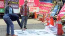 Aktivis menggunakan cat semprot menuliskan kalimat "KPK Shut Down" pada spanduk untuk dibentangkan di depan Gedung Merah Putih, Jakarta, Jumat (13/9/2019). Aksi ini bertepatan dengan terpilihnya Firli Bahuri sebagai Ketua KPK periode 2019-2023 oleh Komisi III DPR RI. (merdeka.com/Dwi Narwoko)
