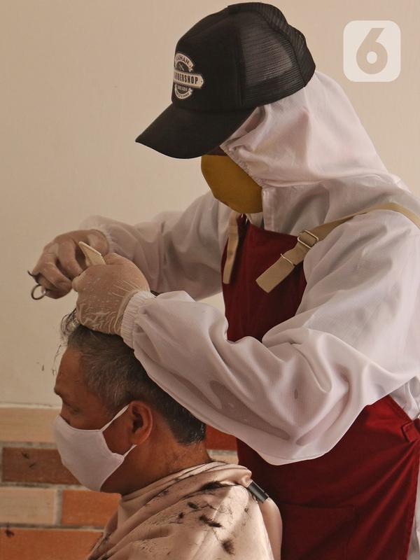 Tukang cukur mengenakan APD saat memotong rambut di halaman rumah pelanggan, Kelapa Dua, Depok, Jawa Barat, Senin (27/4/2020). Penerapan PSBB Kota Depok membuat tukang cukur tersebut menerima jasa panggilan ke rumah dan mengenakan APD untuk mencegah penularan COVID-19. (Liputan6.com/Herman Zakharia)