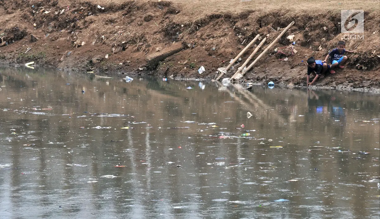 Anak-anak bermain di pinggir aliran Kanal Banjir Barat yang tengah dipenuhi sampah, Jakarta, Senin (22/10). Sampah yang memenuhi aliran kanal pencegah banjir tersebut didominasi plastik dan limbah rumah tangga. (Merdeka.com/Iqbal Nugroho)