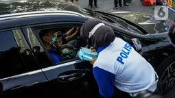 Petugas kepolisian membagikan masker saat sosialisasi pelaksanaan ganjil genap di Kawasan Bundaran HI, Jakarta, Minggu (2/8/2020). Ditlantas Polda Metro Jaya kembali memberlakukan sistem ganjil genap di 25 ruas jalan protokol  DKI Jakarta mulai Senin, 3 Agustus 2020. (Liputan6.com/Faizal Fanani)