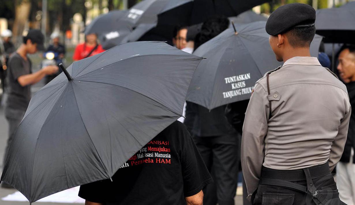 Seorang petugas saat menjaga aksi Kamisan ke-378 di seberang Istana Negara, Jakarta, Kamis (11/12/2014). (Liputan6.com/Miftahul Hayat)