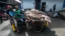 Nelayan mengendarai becak membawa tangkapannya termasuk ikan hiu di sebuah TPI di Brondong, Lamongan, Jawa Timur, Senin (13/3). Meski pemerintah melarang, perburuan ikan hiu masih marak dilakukan nelayan perairan Jawa Timur. (AFP Photo/Juni Kriswanto)