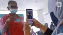 Petugas mengambil foto warga penerima Bantuan Sosial Tunai (BST) di Kelurahan Pondok Benda, Kecamatan Pamulang, Tangerang Selatan, Minggu (10/01/2021). Sebanyak 92.737 kepala keluarga tercatat sebagai penerima BST di wilayah Tangerang Selatan senilai Rp300 ribu. (Liputan6.com/Fery Pradolo)