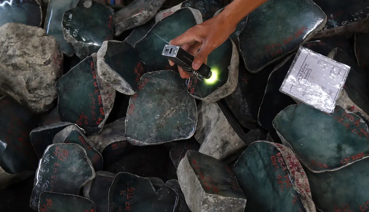Seorang pedagang memeriksa batu giok dalam bentuk bongkahan yang ditampilkan selama Gems Emporium di Naypyitaw, Myanmar, Selasa (13/11). Acara tahunan tersebut dimulai pada Senin dan akan berlangsung hingga 17 November 2018. (AP/Aung Shine Oo)